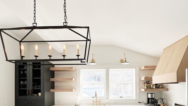 A modern kitchen with a marble island, black cabinetry, and a unique geometric pendant light. - Charming Cottage steps to restaurants, shops & slopes (Park City)