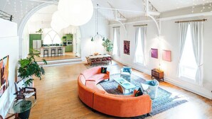 A spacious living area with a curved orange sofa, a dining table, and a kitchen in the background. - Find Your Sanctuary at The Church (Helena)