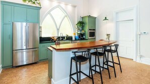 A modern kitchen with a central island, stainless steel appliances, and green cabinetry. - Find Your Sanctuary at The Church (Helena)