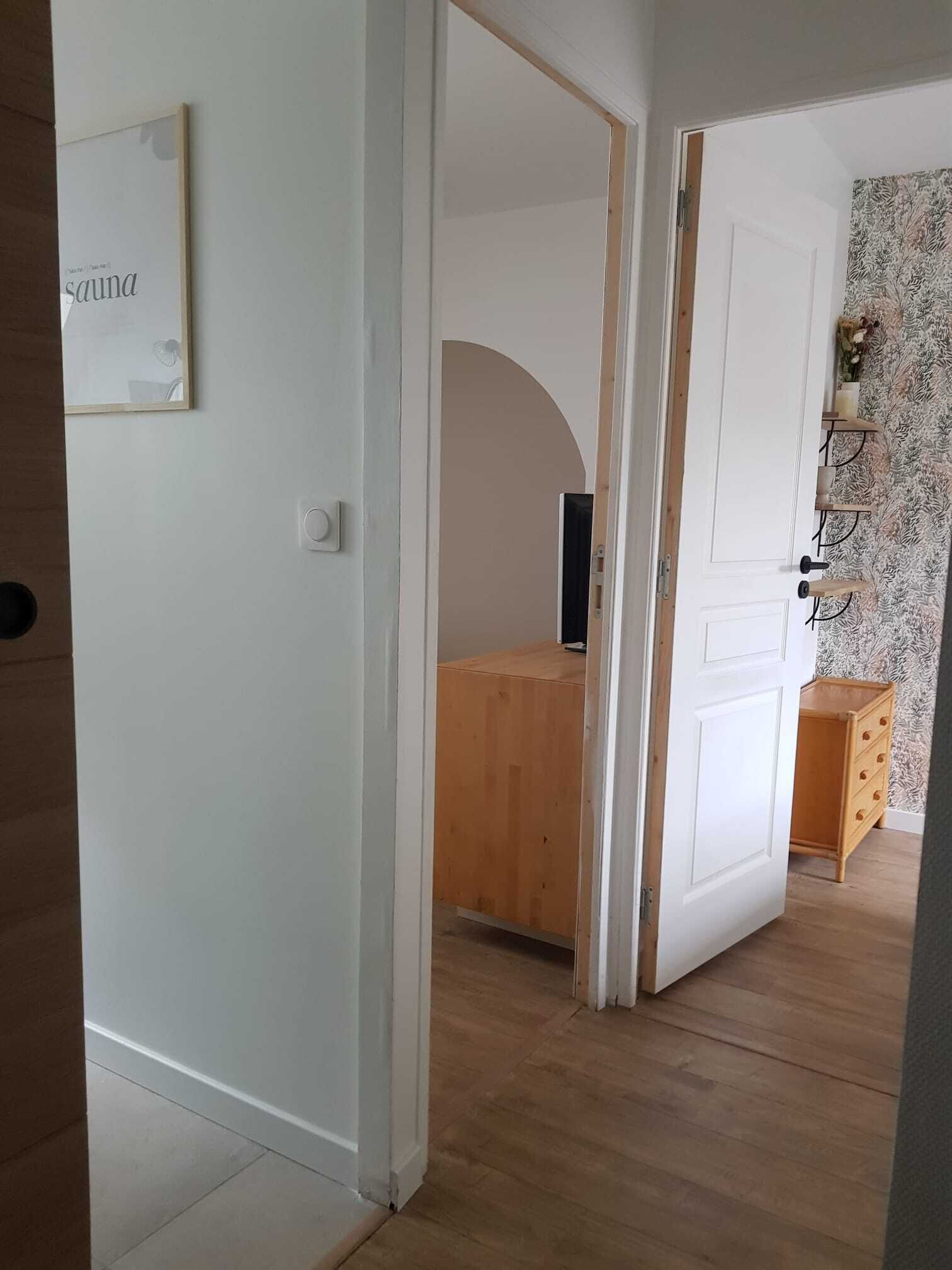 A hallway with a wooden cabinet, a white door, and a wall-mounted sign that reads "sauna".
