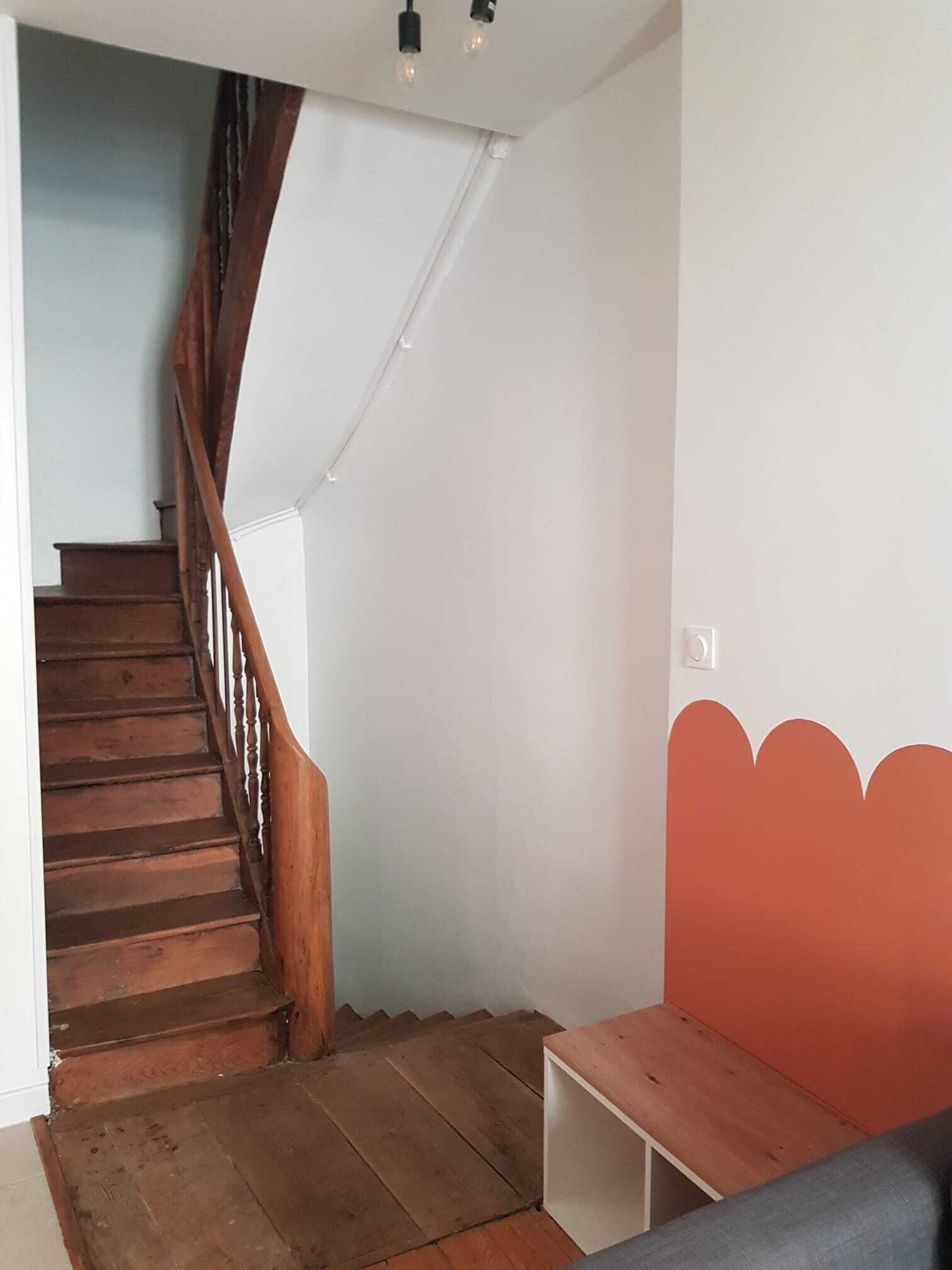 Een trap met houten treden en een houten leuning die uitkomt op een plateau.