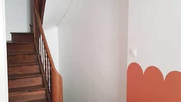 Een trap met houten treden en een houten leuning die uitkomt op een plateau.