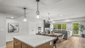 A spacious kitchen with a central island, pendant lighting, and a view to the outdoors.