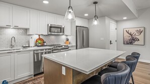 A modern kitchen with white cabinets, stainless steel appliances, and a large island with bar stools.