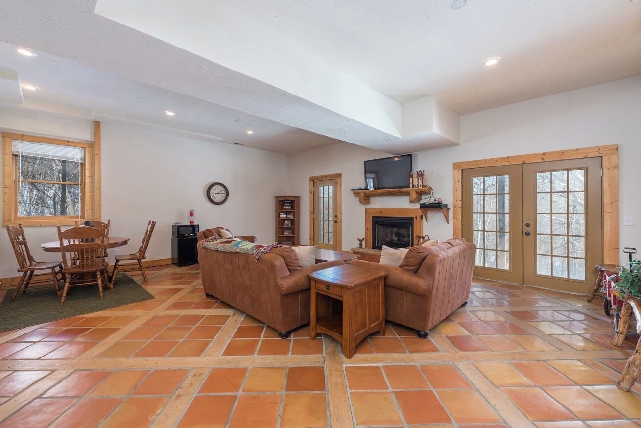 Un salón amplio con chimenea, televisor y comedor con mesa y sillas.
