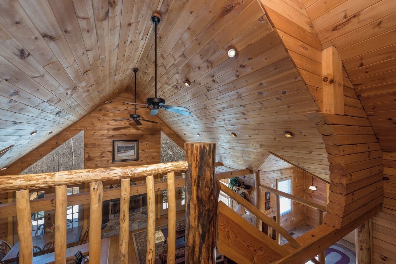 Un interior de madera con techo inclinado, vigas de madera y una escalera.