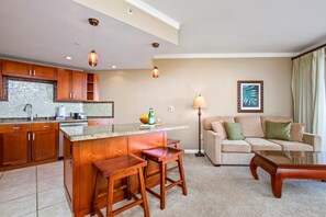 Eine moderne Küche mit einer zentralen Kochinsel, Holzbarhocker, einer Couch und einer Stehlampe.