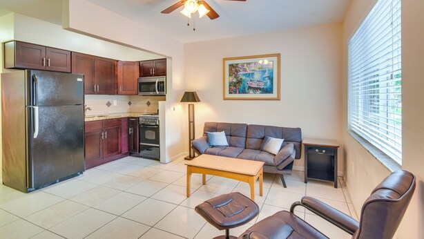A compact living space with a kitchenette, a ceiling fan, a sofa, a coffee table, and a window with blinds. - Your Ideal 30-Day Furnished Retreat in Hallandale! (Hallandale Beach)