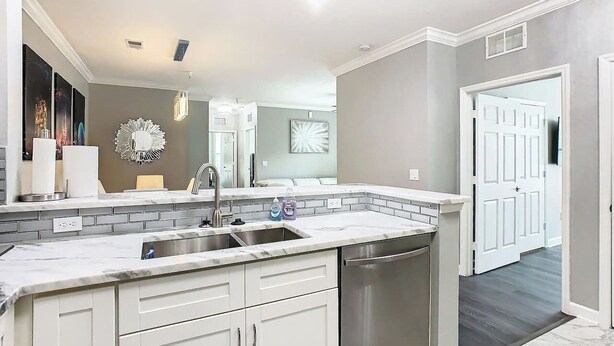 A modern kitchen with a built-in dishwasher, a stainless steel sink, and a white countertop. - Luxury Modern 3BR Near Disney (Davenport)