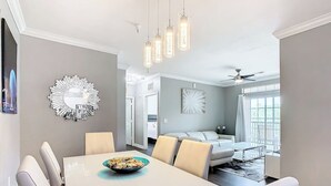 A dining area with a white table and chairs, a decorative mirror, and pendant lights. - Luxury Modern 3BR Near Disney (Davenport)