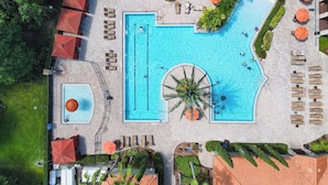 An aerial view of a resort with a large swimming pool, sun loungers, umbrellas, and a small hot tub. - Luxury Modern 3BR Near Disney (Davenport)