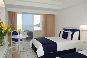 Une chambre d’hôtel avec un lit, un bureau, une chaise et une vue sur la mer.