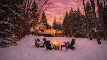 Winter sunset from 3 Mile Lake, with the cottage lit warmly and a cozy bonfire.