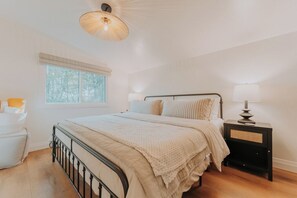 A bedroom with a bed, bedside tables, a window, and a hanging light fixture. - 6BR Lakefront Muskoka Sunset Retreat w/ Hot Tub, Dock & Firepit (Utterson)
