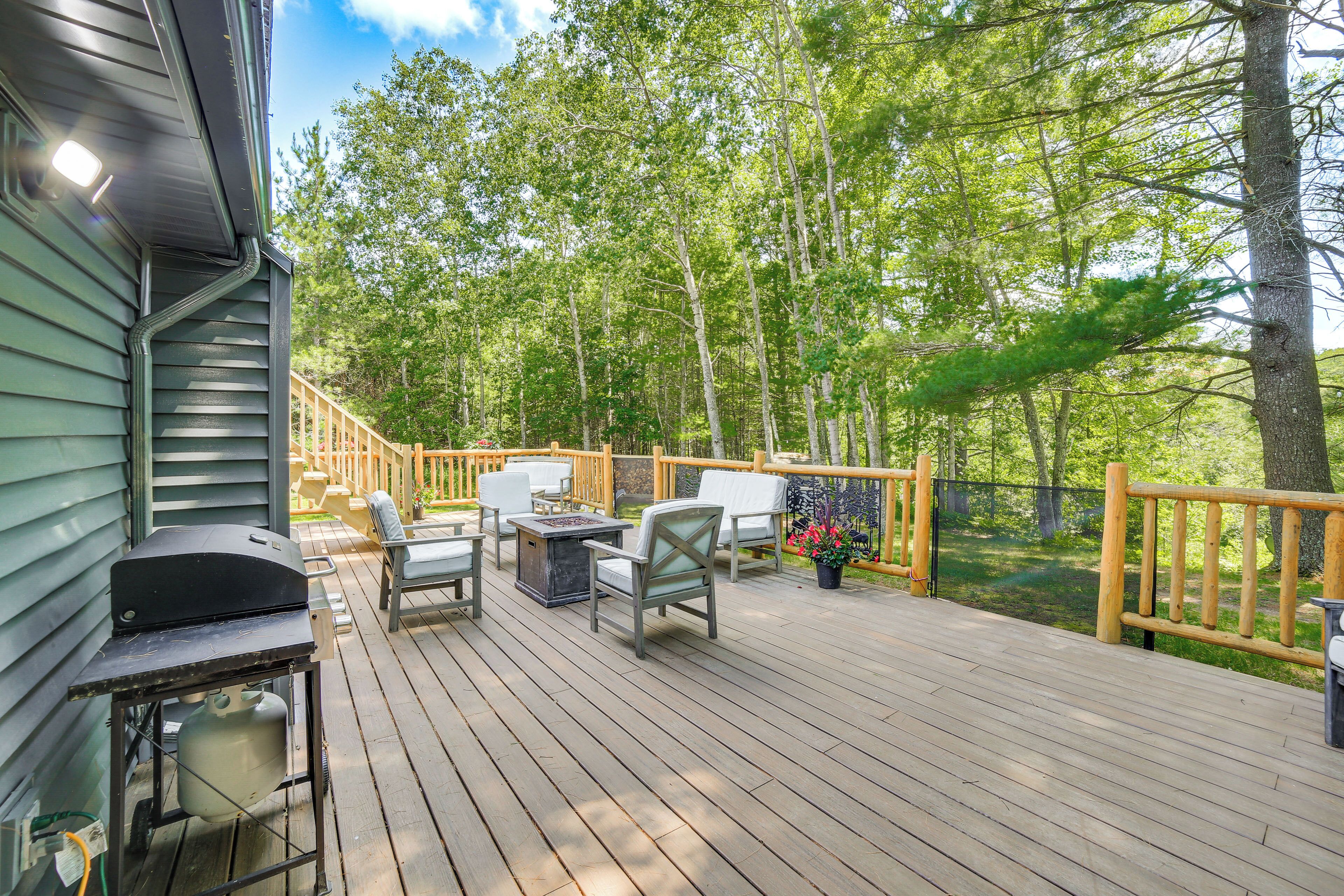 A wooden deck with outdoor furniture and a grill.
