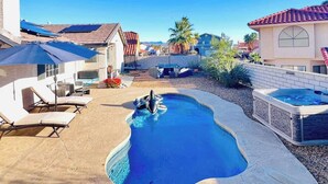 Un patio trasero con piscina, sillas de descanso y un jacuzzi.