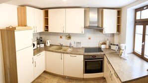 A compact kitchen with white cabinets, a built-in oven, a sink, and a window.
