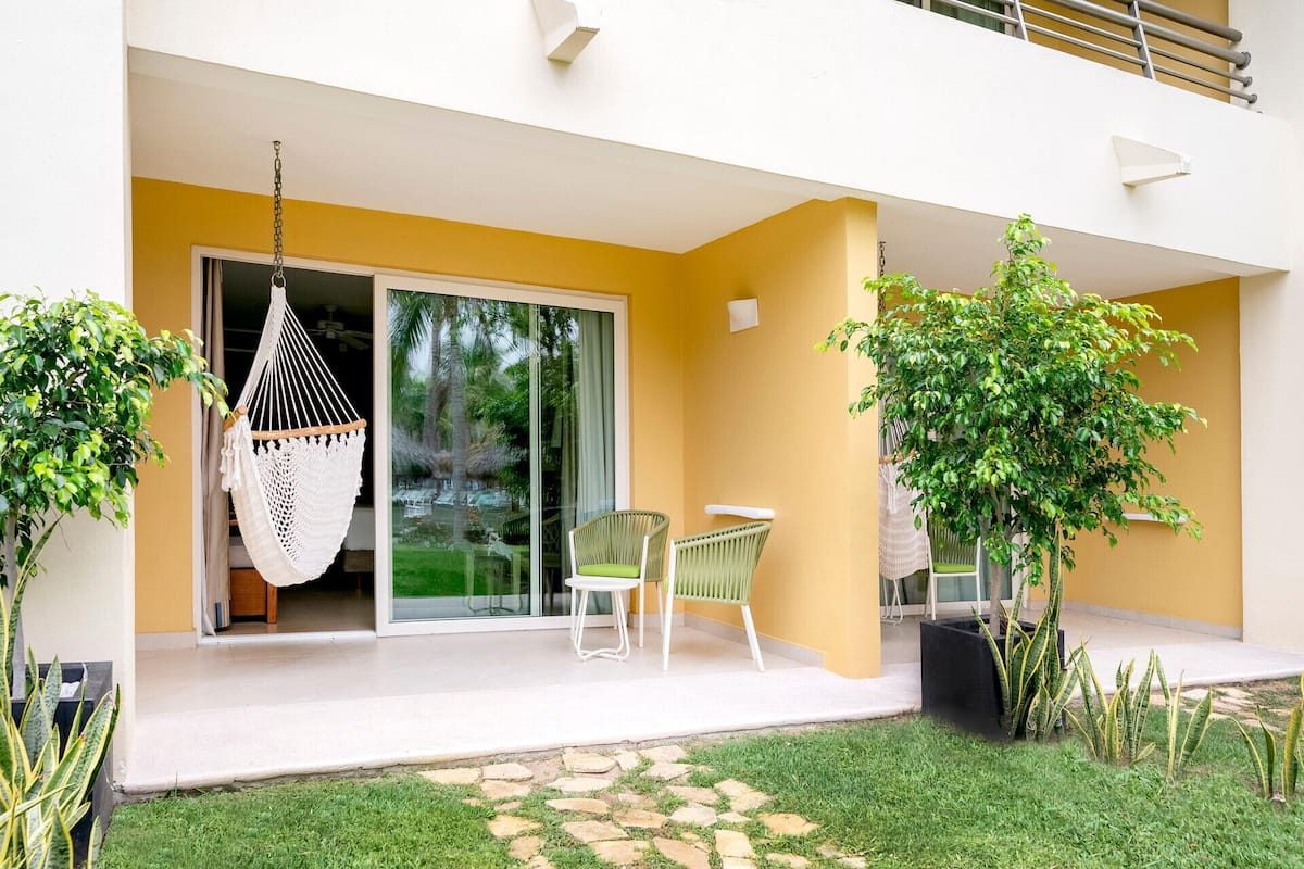 A modern outdoor patio with a hammock, two chairs, and a small garden area.