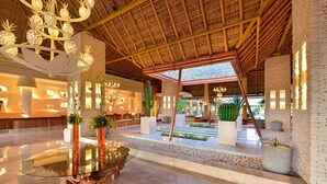 A spacious lobby with a glass coffee table, a reception desk, and a thatched roof structure. - Iberostar Selection Playa Mita - All Inclusive (Punta de Mita)