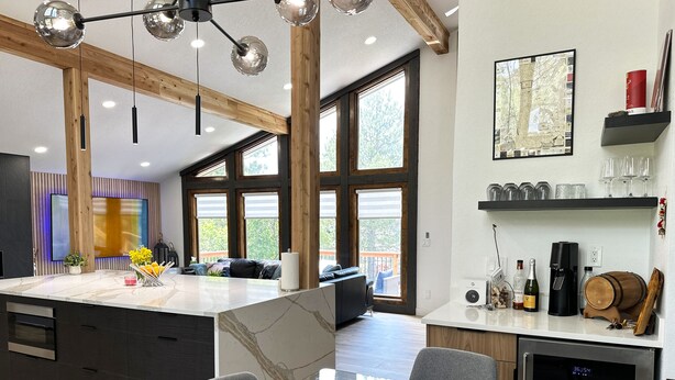 A modern kitchen with a large island, built-in appliances, and a dining area with glass tables and chairs. - Charming 3-bedroom house Parker (Parker)