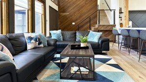 A modern living room with a black leather sofa, a wooden coffee table, and a geometric patterned rug. - Charming 3-bedroom house Parker (Parker)