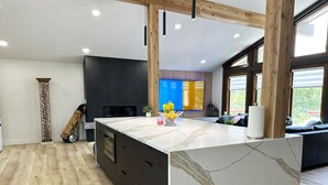 A modern kitchen with a marble countertop, dark cabinetry, and a large window providing natural light. - Charming 3-bedroom house Parker (Parker)