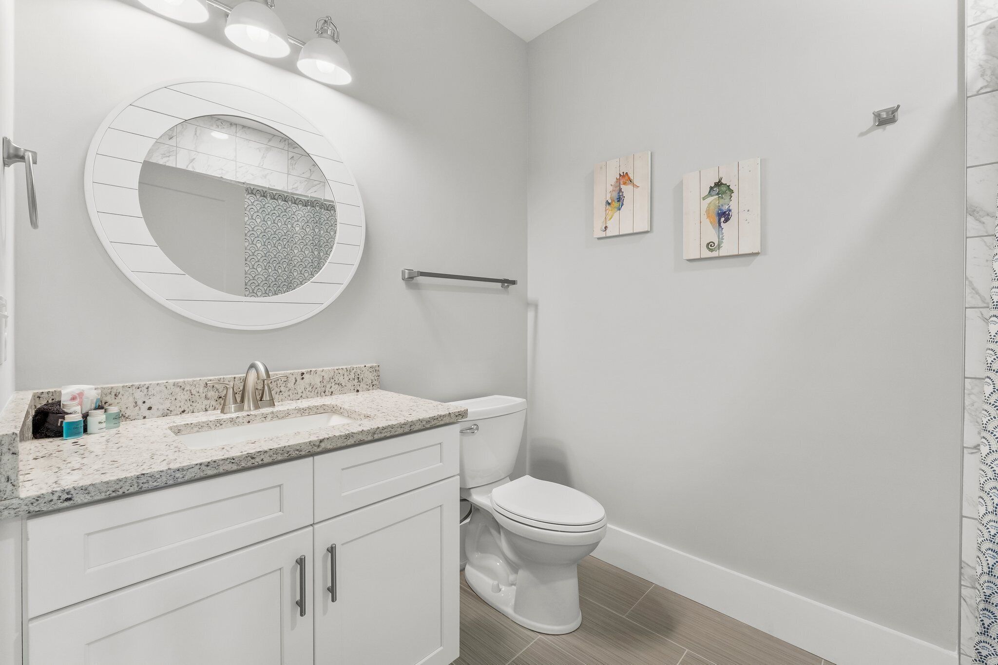 Un baño moderno con un espejo redondo, un inodoro y un lavabo.