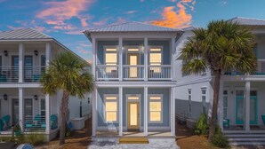 A two-story beachfront property with a balcony, palm trees, and a beachside view. - 22704 Front Beach Road Ocean Breeze (Panama City Beach)
