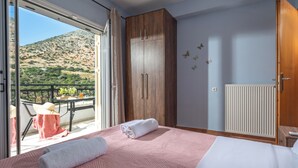 Ein Schlafzimmer mit einem Bett, einem Holzschrank, einem Heizkörper und einem Balkon mit Tisch und Stühlen.