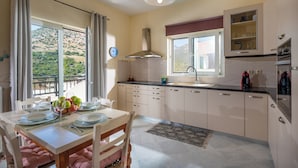 Eine moderne Küche mit Essbereich, großen Fenstern und Blick auf eine gebirgige Landschaft.