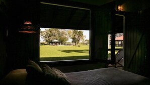 Una habitación con un ventanal que ofrece vistas a un espacio verde y un edificio con sombrillas.