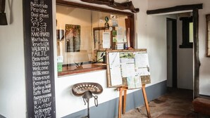 Una zona de recepción con un mostrador de madera, un tablón de anuncios con varios avisos y una bicicleta apoyada en la pared.