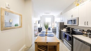 A modern kitchen with white cabinets, stainless steel appliances, and a wooden island with blue placemats. - King Bed, Free Parking, Near Stadium (Cincinnati)
