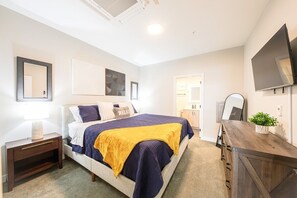 Une chambre à coucher comprenant un lit, une table de chevet, une commode, un miroir et des œuvres d’art accrochées aux murs.