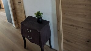 En hall med trädörrar, ett mörkt träbord med en växt på och en svart väggdekoration som föreställer ett rådjurshuvud.