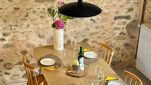 A dining table set with plates, cutlery, and glasses, surrounded by wooden chairs, against a stone wall backdrop. - Flore (Vive le Vert)

At Vive le Vert we believe holidays are precious. (Bussière-Badil)