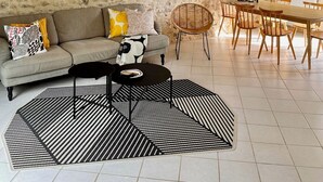 A cozy living room with a stone wall, wooden beams, a sofa, a dining table, and a patterned rug. - Flore (Vive le Vert)

At Vive le Vert we believe holidays are precious. (Bussière-Badil)