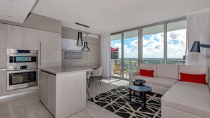 A modern kitchen with built-in appliances, a dining area with a round table, and a living area with a sofa and a view of the city. - Stunning 25th-Floor Views in Hollywood (Hollywood)