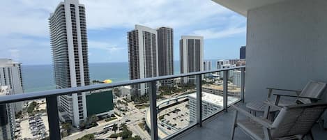 Un balcón con vistas a edificios altos, una piscina y cielo despejado.