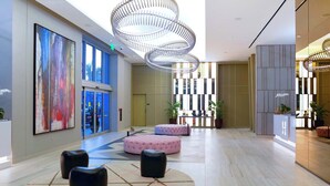 A spacious lobby with a modern chandelier, large windows, and a reception desk. - Stunning 25th-Floor Views in Hollywood (Hollywood)