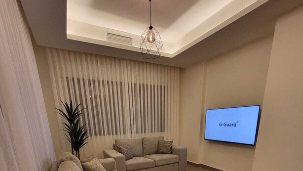 Una sala de estar moderna con un sofá seccional, un televisor montado en la pared y una lámpara decorativa.