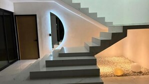 Una escalera moderna de diseño curvo que conduce a una zona de descanso con un pequeño conjunto de asientos y un objeto esférico.