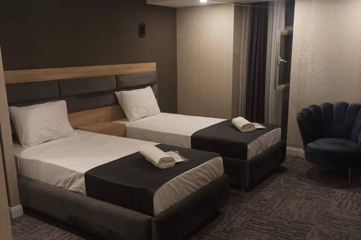 Habitación de hotel con dos camas, una silla y piso alfombrado.