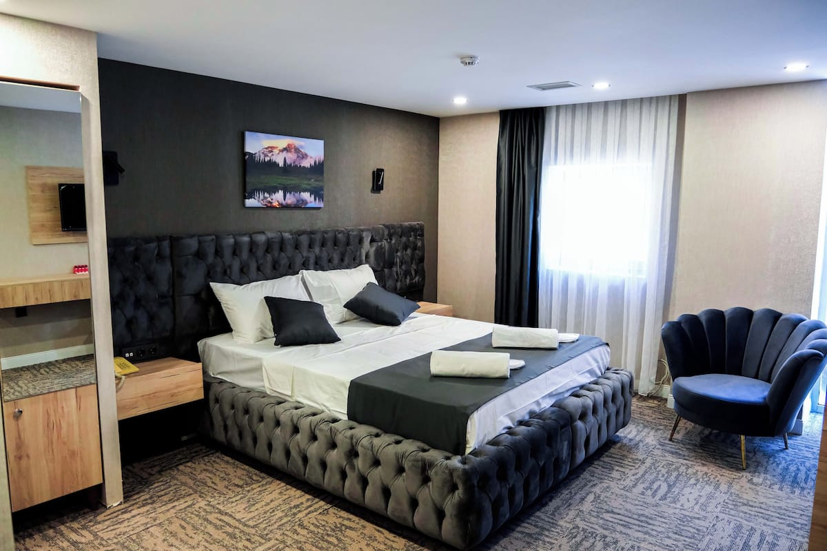 Habitación de hotel moderna con una cama grande, un escritorio, una silla y vistas al exterior.