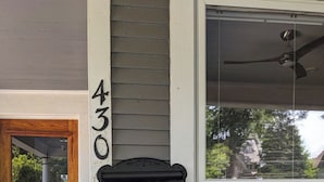 Hausnummer 430, eine Holztür und ein Fenster mit Blick auf Bäume und ein Auto.