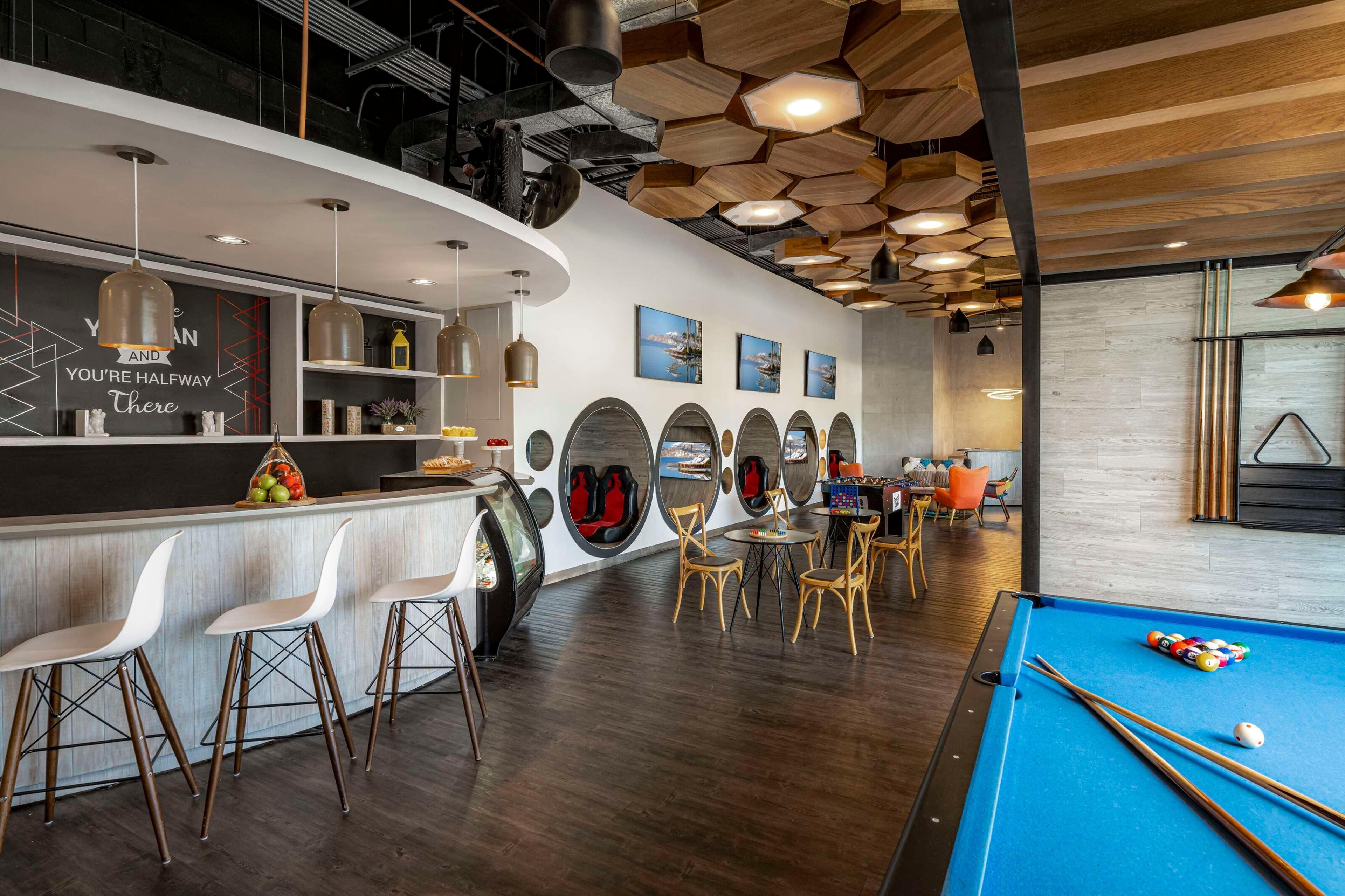 Zona de bar moderna con mesa de billar, asientos y piscina.