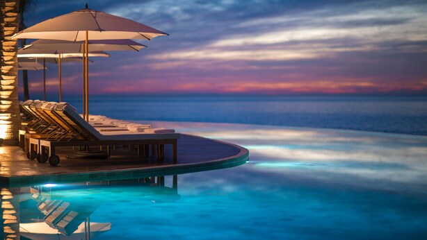 A poolside area with lounge chairs and umbrellas, overlooking a calm sea at sunset. - Grand Velas Los Cabos - All Inclusive (Cabo San Lucas)
