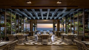 A restaurant with a view of the ocean, featuring wicker furniture and a checkered floor. - Grand Velas Los Cabos - All Inclusive (Cabo San Lucas)