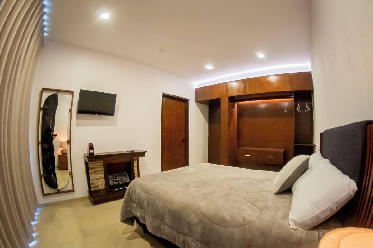 Une chambre d’hôtel comprenant un lit, une armoire en bois, un téléviseur à écran plat et un miroir.