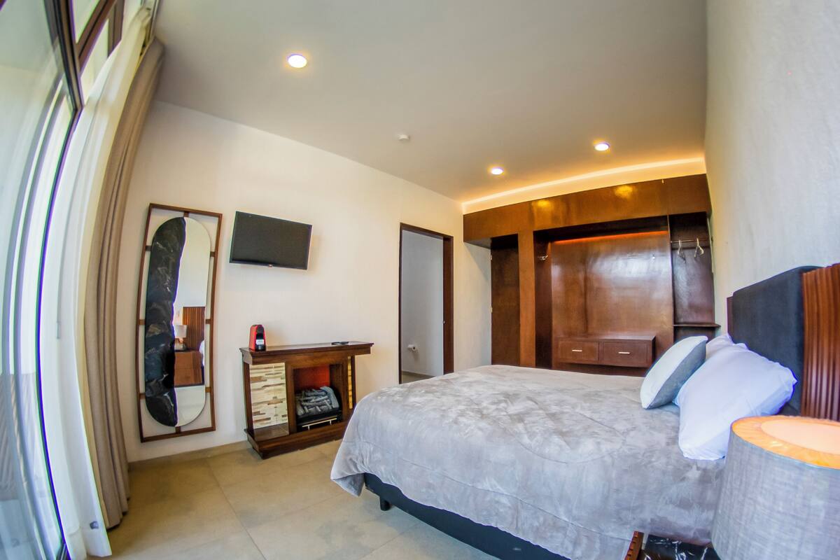 Une chambre à coucher avec un lit, une télévision, une armoire et un miroir.